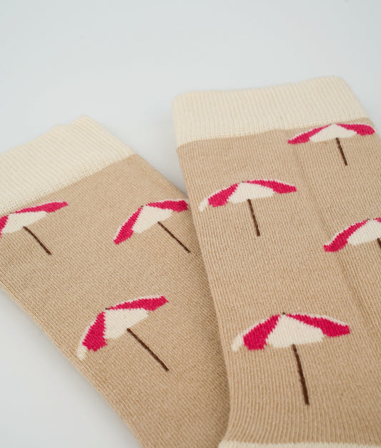 Chaussettes fantaisie beiges en coton biologique à motif de parasols de plage. Fabriquées en Europe, elles offrent un confort optimal grâce à leurs zones renforcées et leurs finitions plates sans couture.