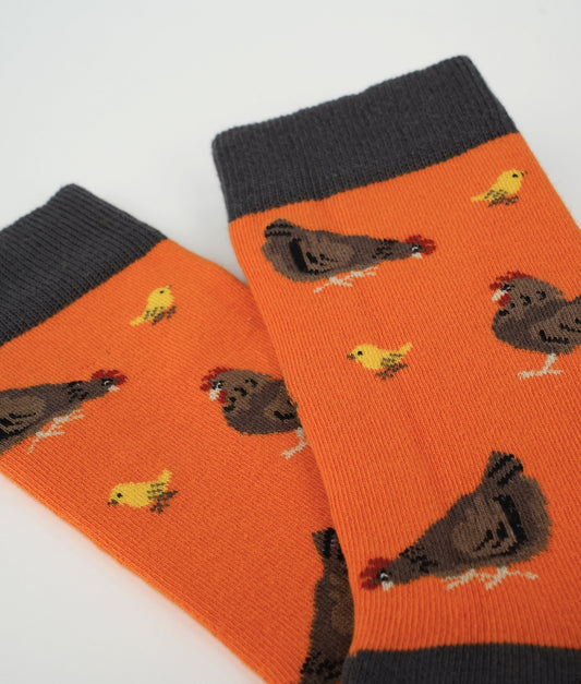 Chaussettes fantaisie orange à motif de poules et poussins. Fabriquées en Europe en coton biologique, elles allient confort, douceur et originalité au quotidien.