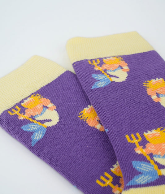 Chaussettes fantaisie violettes et jaune pastel en coton biologique à motif de Poseidons. Fabriquées en Europe, elles offrent un confort optimal grâce à leurs zones renforcées et leurs finitions plates sans couture.