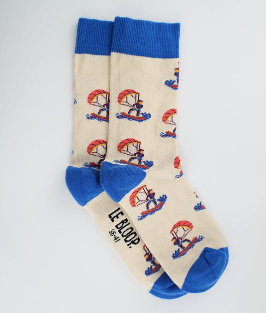 Chaussettes fantaisie beiges et bleues en coton biologique à motif de kitesurfeurs. Fabriquées en Europe, elles offrent un confort optimal grâce à leurs zones renforcées et leurs finitions plates sans couture.