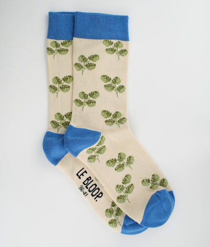 Chaussettes fantaisie beiges et bleues en coton biologique à motif de feuilles de Monstera. Fabriquées en Europe, elles offrent un confort optimal grâce à leurs zones renforcées et leurs finitions plates sans couture.