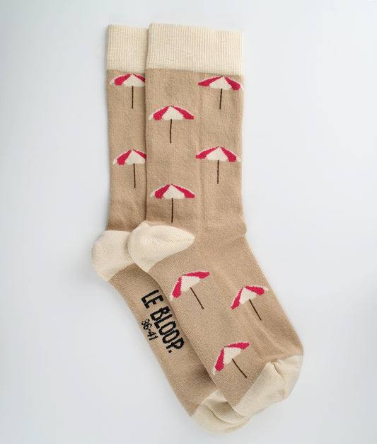 Chaussettes fantaisie beiges en coton biologique à motif de parasols de plage. Fabriquées en Europe, elles offrent un confort optimal grâce à leurs zones renforcées et leurs finitions plates sans couture.