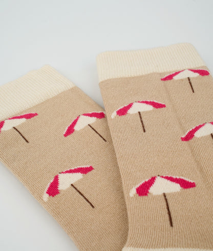 Chaussettes fantaisie beiges en coton biologique à motif de parasols de plage. Fabriquées en Europe, elles offrent un confort optimal grâce à leurs zones renforcées et leurs finitions plates sans couture.