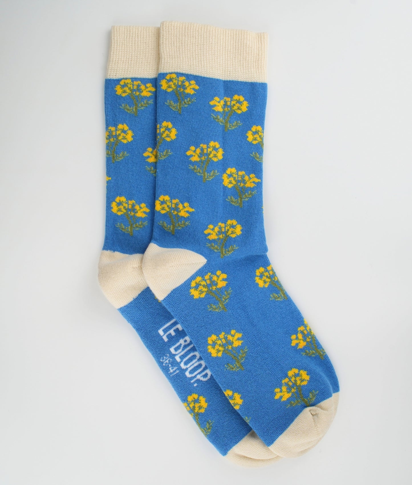 Chaussettes fantaisie bleues et crème en coton biologique à motif de fleurs immortelles. Fabriquées en Europe, elles offrent un confort optimal grâce à leurs zones renforcées et leurs finitions plates sans couture.