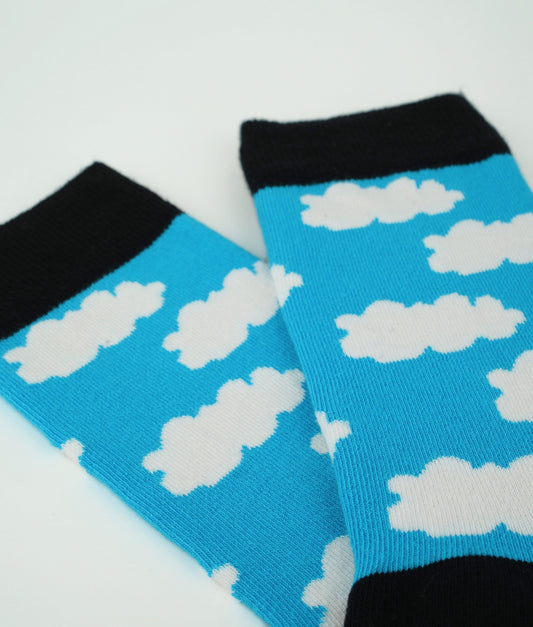 Chaussettes fantaisie bleues à motif de nuages blancs, inspirées des ciels d’été.