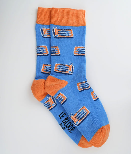 Chaussettes fantaisie bleues en coton biologique à motif de boîtes de sardines. Fabriquées en Europe, elles offrent un confort optimal grâce à leurs zones renforcées et leurs finitions plates sans couture.