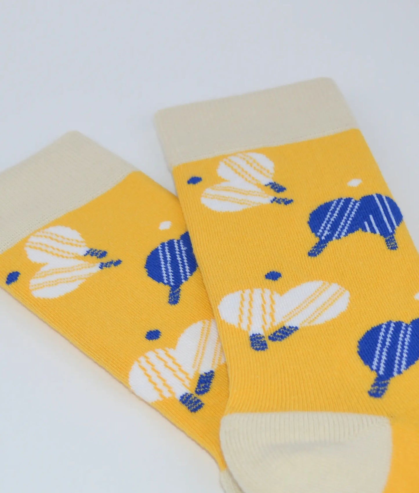 Chaussettes fantaisie crème et jaune à motif raquettes de plage, en coton biologique, fabriquées au Portugal, confortables et résistantes.