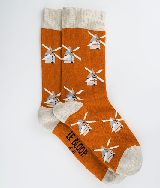 Chaussettes fantaisie orange à motif de moulins à vent. Tricotées en Europe en coton biologique, elles offrent un confort durable grâce à leurs renforts au talon et à la pointe ainsi qu'à leurs finitions plates sans couture.