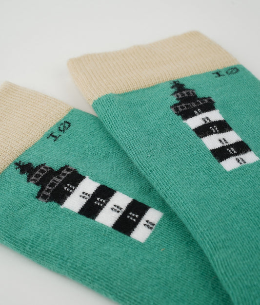 Chaussettes fantaisie en coton biologique à motif de phares du bord de mer. Fabriquées en Europe, elles offrent un confort optimal grâce à leurs zones renforcées et leurs finitions plates sans couture.