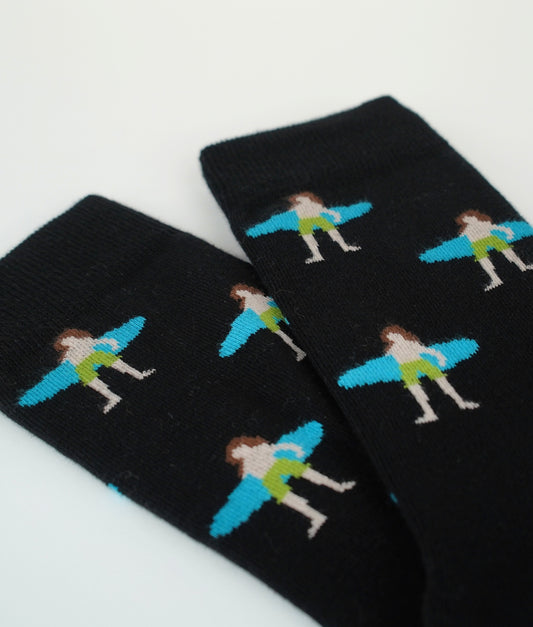 Chaussettes fantaisie noires à motif de surfeurs. Fabriquées en Europe en coton biologique, elles offrent confort, douceur et résistance pour un style décontracté.