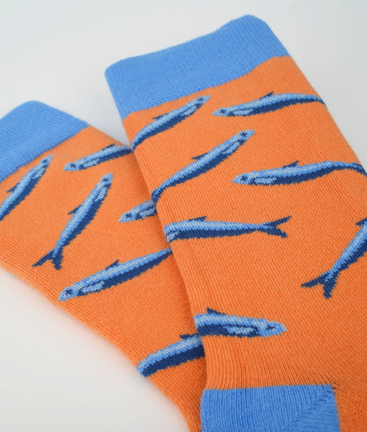 Chaussettes fantaisie orange en coton biologique à motif de sardines bleues. Fabriquées en Europe, elles offrent un confort optimal grâce à leurs zones renforcées et leurs finitions plates sans couture.