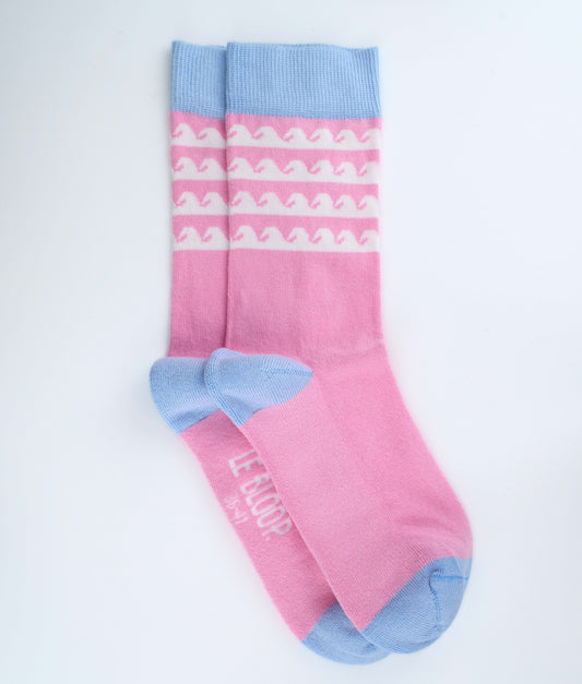 Chaussettes fantaisie roses en coton biologique à motif de vagues blanches. Fabriquées en Europe, elles offrent un confort optimal grâce à leurs zones renforcées et leurs finitions plates sans couture.