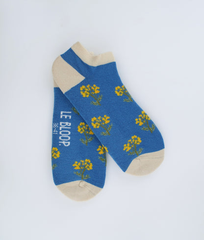 Socquettes fantaisie bleues à motif de fleurs immortelles. Confectionnées en Europe en coton biologique, elles offrent une sensation de douceur et un style floral inspiré de la nature.