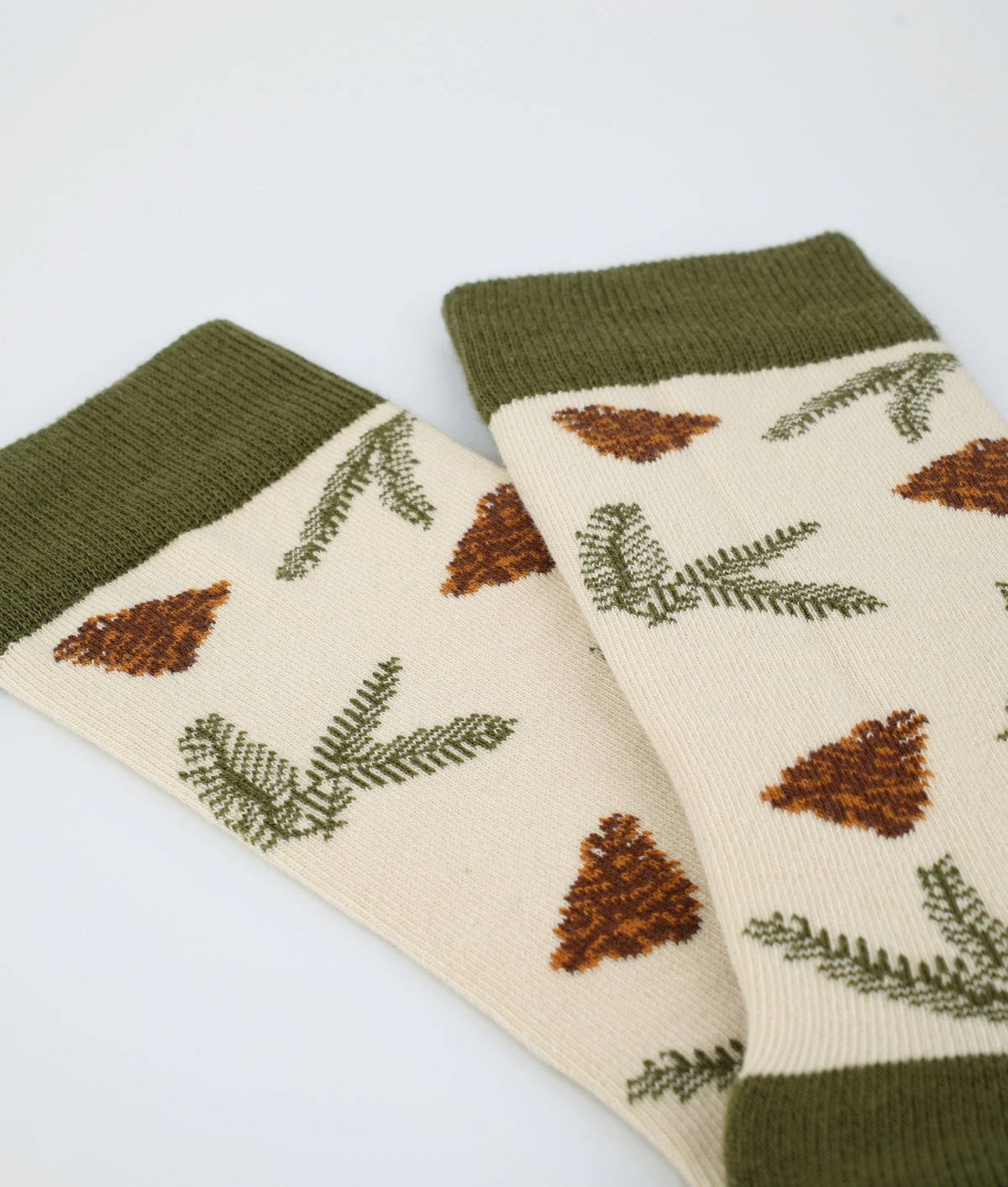 Chaussettes fantaisie kaki et beige à motif de pommes de pin. En coton biologique et tricotées en Europe, elles offrent un confort durable et un style inspiré de la nature.