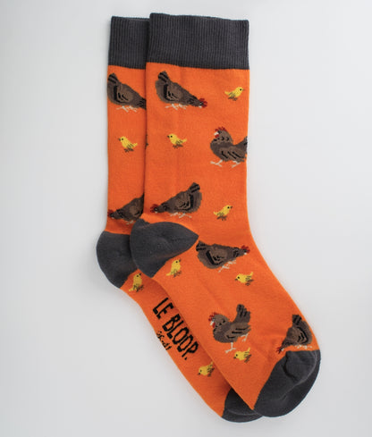 Chaussettes fantaisie orange à motif de poules et poussins. Fabriquées en Europe en coton biologique, elles allient confort, douceur et originalité au quotidien.