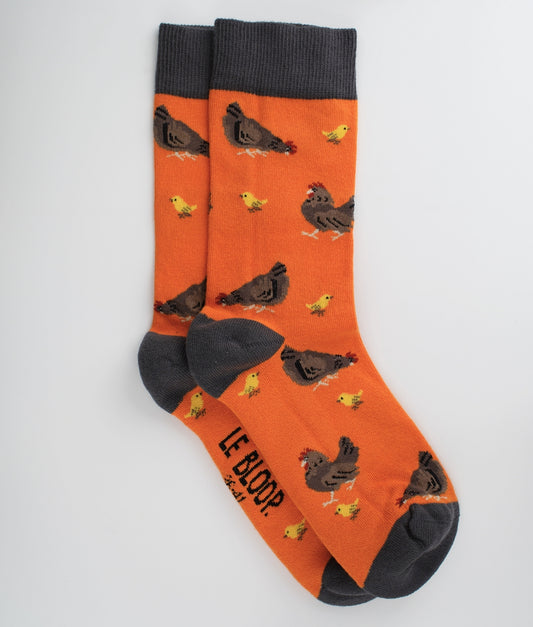 Chaussettes fantaisie orange à motif de poules et poussins. Fabriquées en Europe en coton biologique, elles allient confort, douceur et originalité au quotidien.
